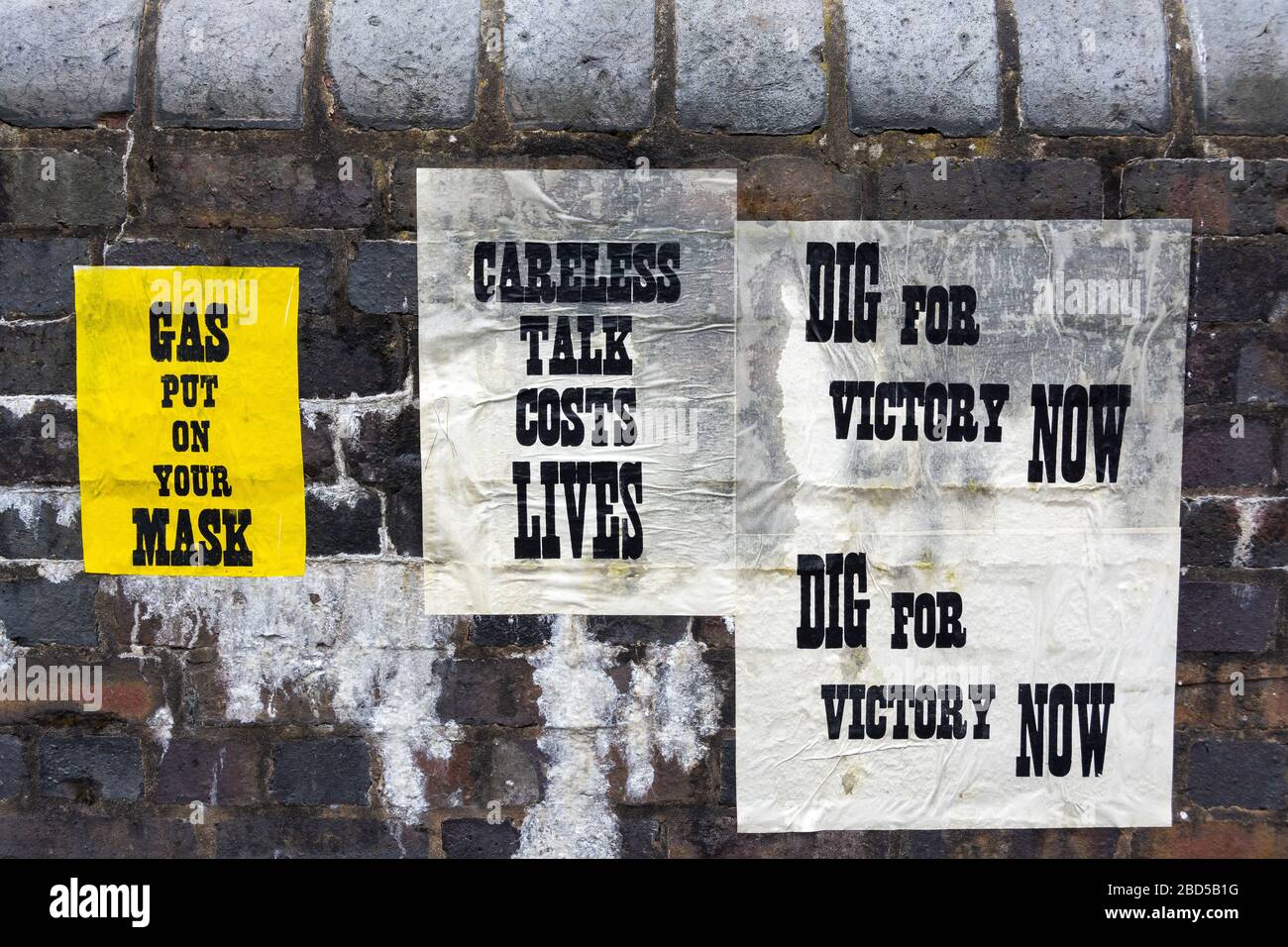 Wartime posters plastered on brick wall Stock Photo