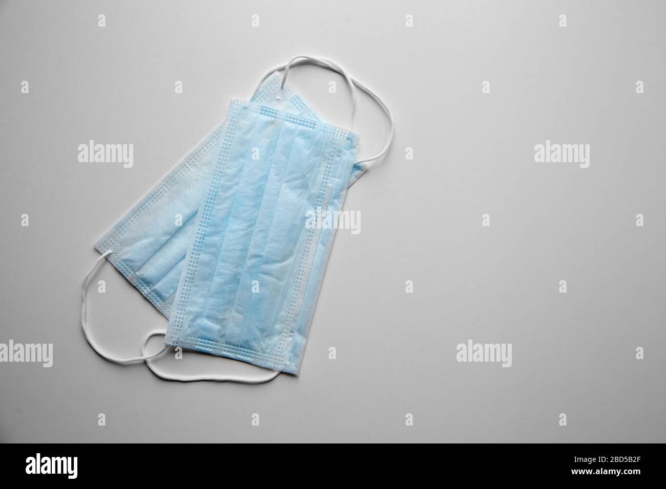 Face masks reduce the chance of spreading airborne diseases. Blue disposable medical sanitary surgical masks on white table, top view. Shortage of sur Stock Photo