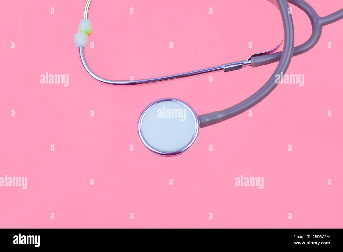 One side of a medical stethoscope isolated on a pink color empty paper ...