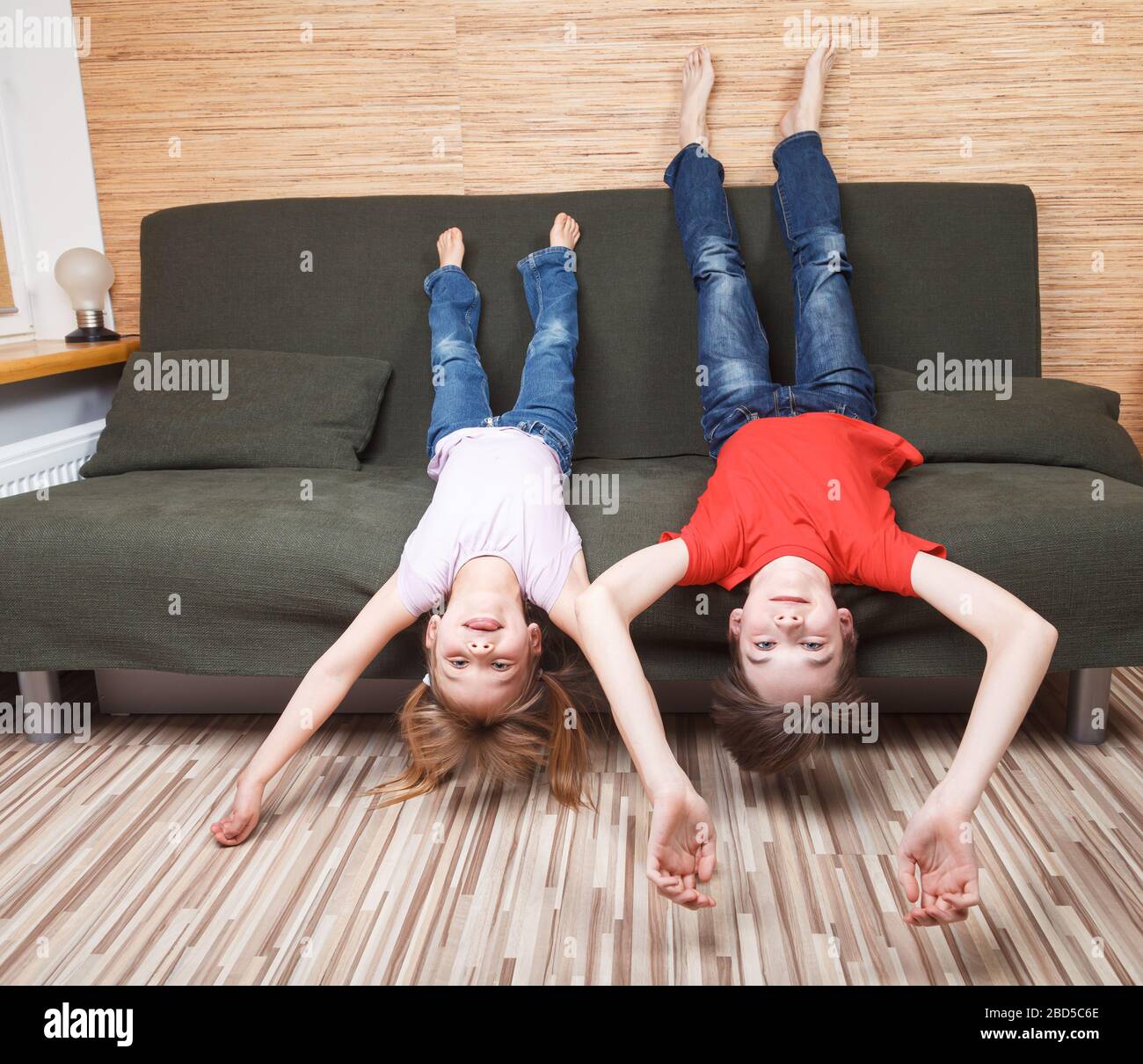 Siblings laying on couch stuck at home being in self-isolation. Quarantine and lockdown protective measures against spreading of coronavirus pandemic Stock Photo