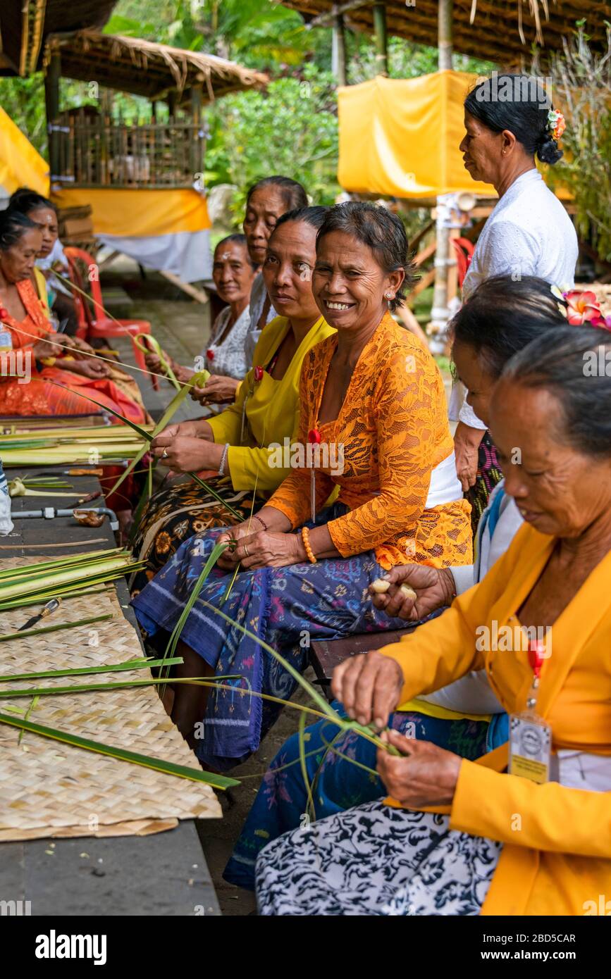 Vertical view of ladies making decorations to offer at a temple in Bali, Indonesia. Stock Photo