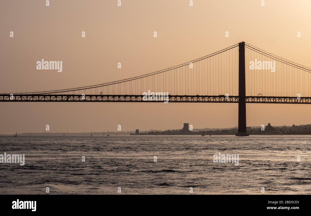 Ponte 25 de Abril, River Tagus, Portugal. A backlit dusk view of the iconic Lisbon suspension bridge over the River Tagus between Lisbon and Almeida. Stock Photo