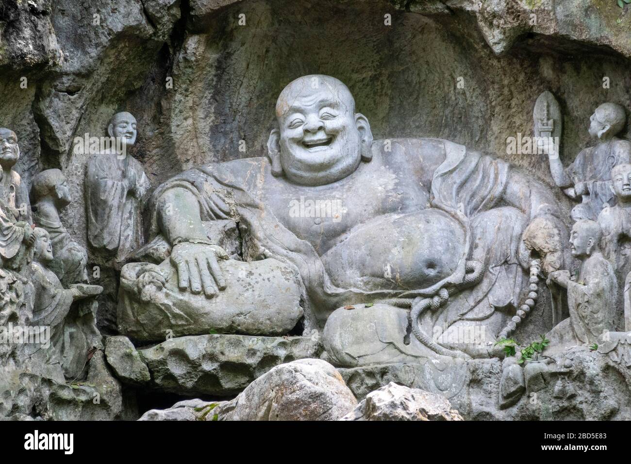 laughing Buddha Maitreya and disciples rock-cut sculpture, Felai Feng grottoes, Lingyin Temple, West Lake, Hangzhou, Chins Stock Photo