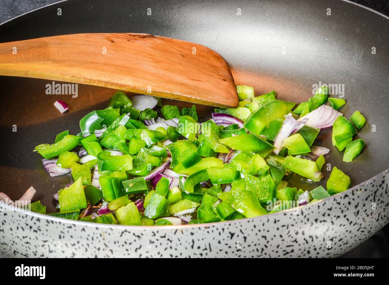 Cooking sliced onions and green peppers on a frying pan close up Stock
