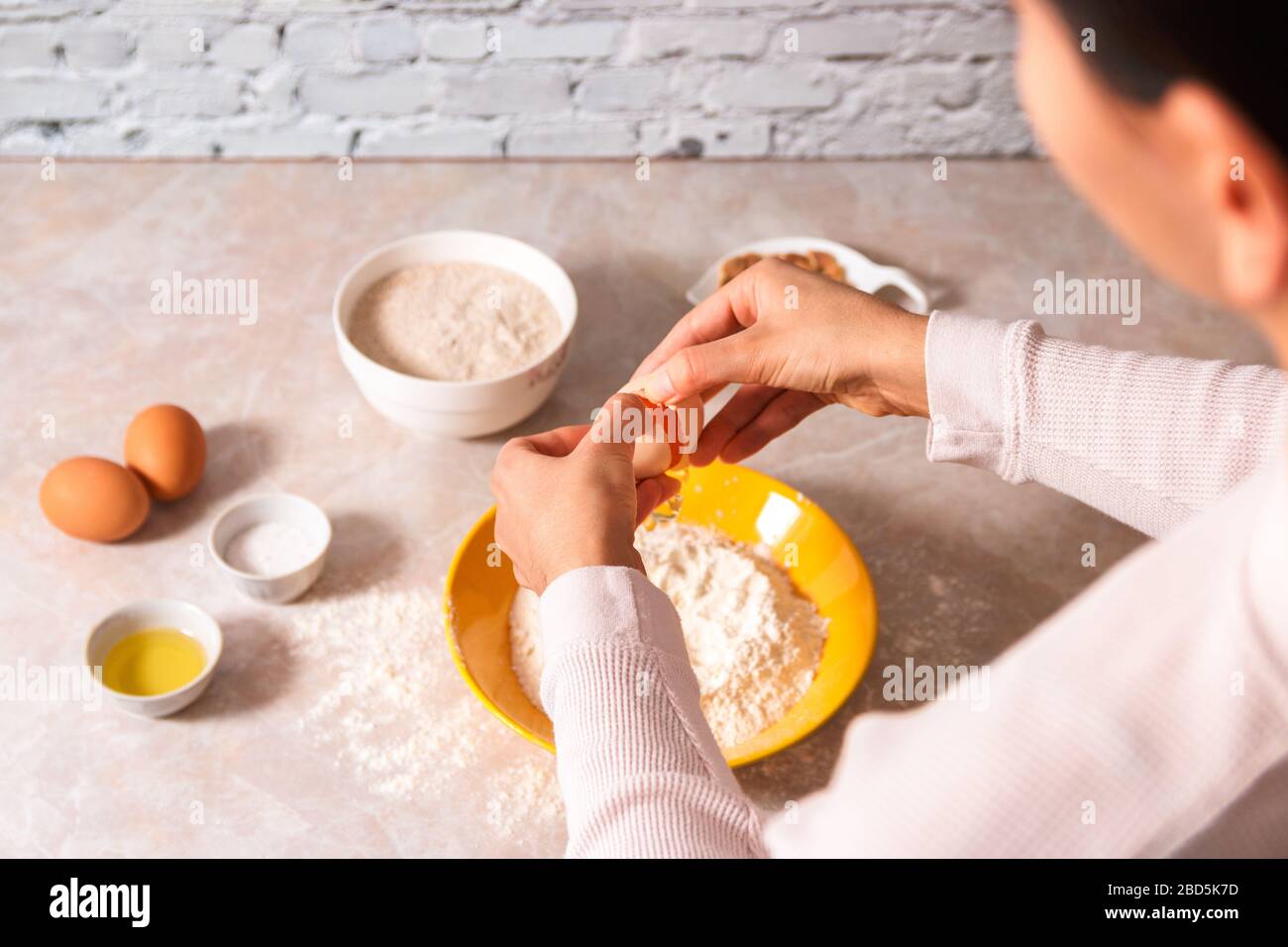 homemade bread baking. closeup woman hands adding egg in flour, dough