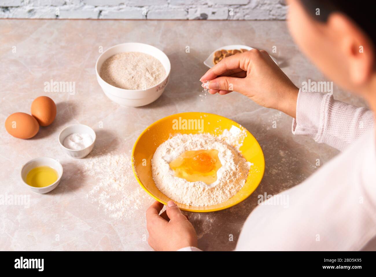 homemade bread baking. closeup woman hands adding salt in flour, dough