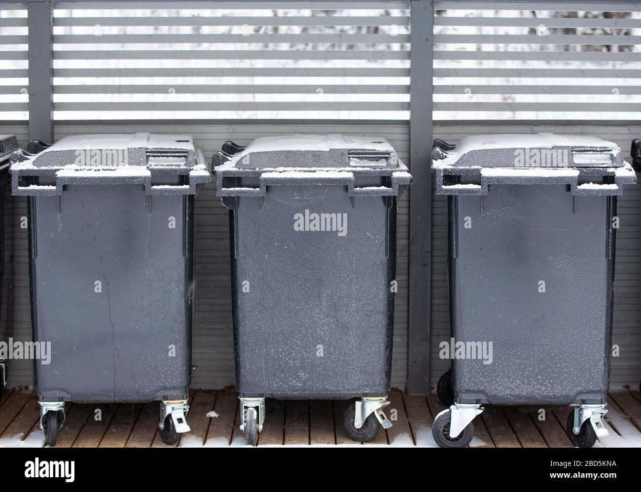 Three 400 litre grey plastic one household trash bins in row outdoors ...