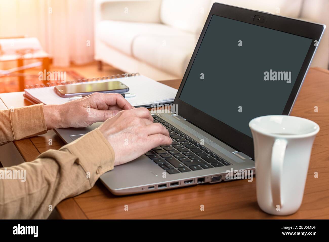 Businesswoman working from home using laptop and smartphone during the coronavirus pandemic Stock Photo