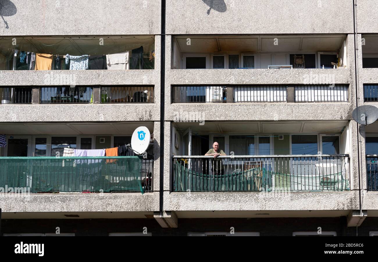 Leith, Edinburgh, Scotland, UK. 7 April 2020. In the third week of the nationwide coronavirus lockdown life in Leith continues although the streets are mostly deserted and shops closed. Pictured; Elderly man on balcony in his flat in Cables Wynd House apartment block. Stock Photo