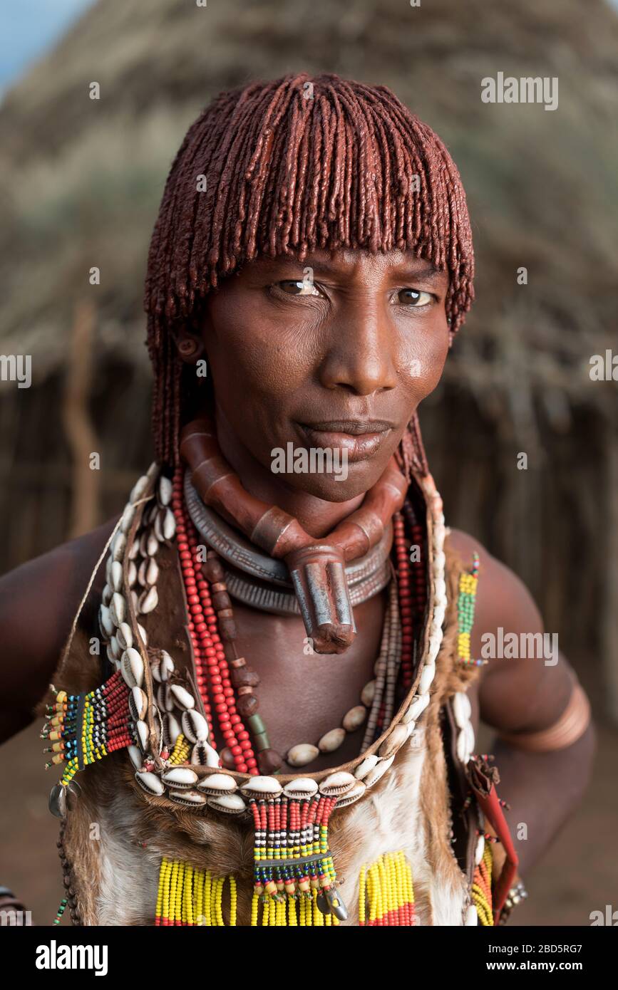 Wearing three necklaces of a first wife, hair braided with butter and