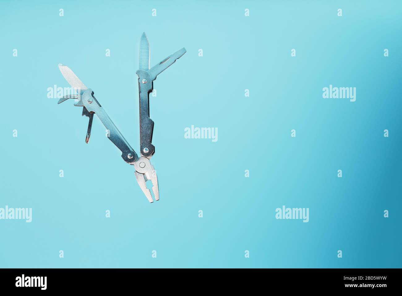 The multitool multi-function tool hovers on a blue background. The concept of an expanded multi-tool with free space. Stock Photo