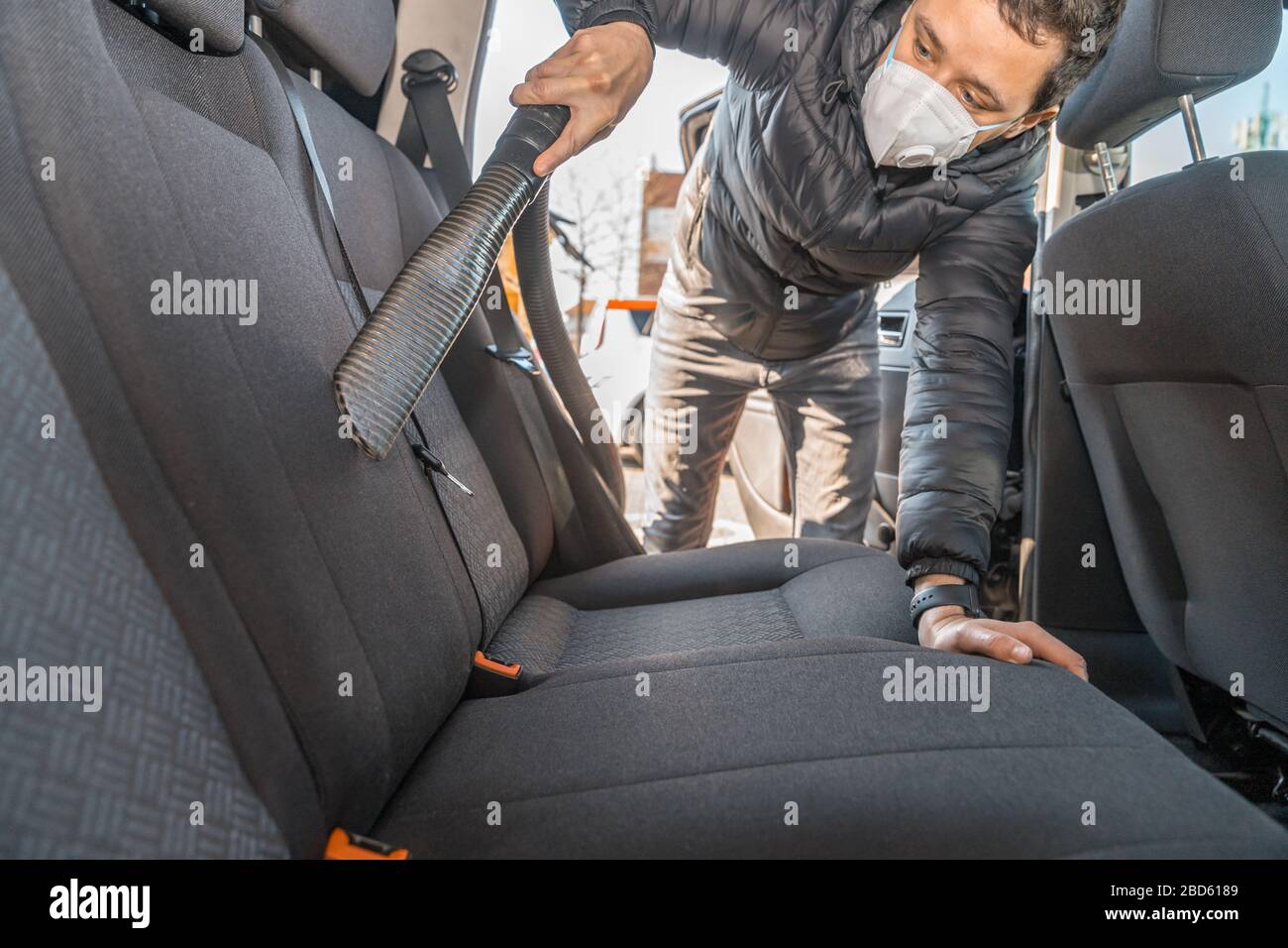 The specialist cleans the chair in the car with a washing vacuum cleaner  Stock Photo