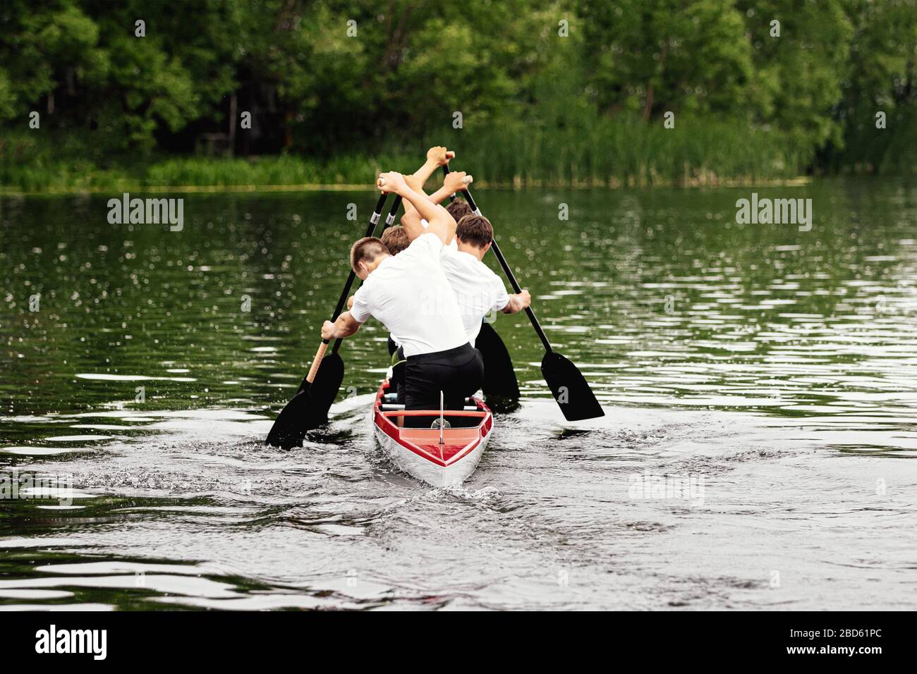 back four athletes canoeist paddling in canoe on lake Stock Photo
