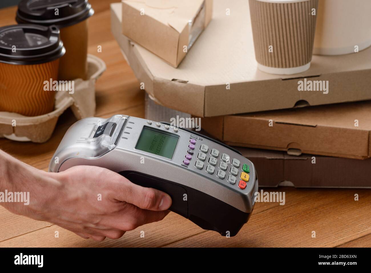 Cashier holding a POS terminal to customer to pay Stock Photo - Alamy