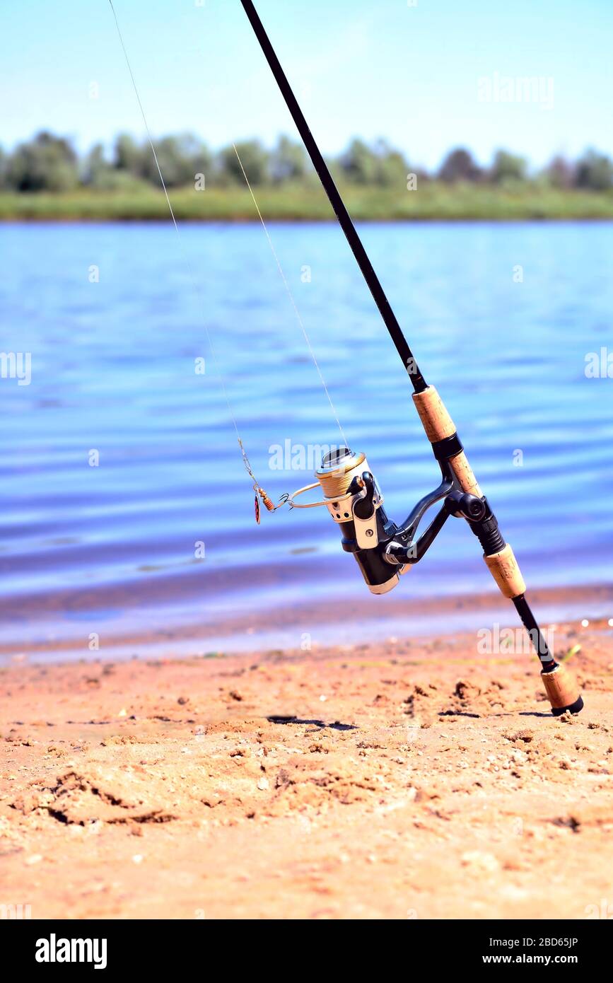 fishing rod with reel on the background of the river, blue water