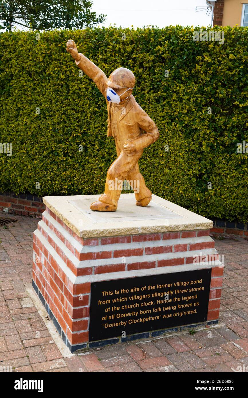 “Clockpelter” statue wearing a medical face mask during the Covid-19 Corona Virus pandemic. Great Gonerby, Grantham, Lincolnshire, England. April 2020 Stock Photo
