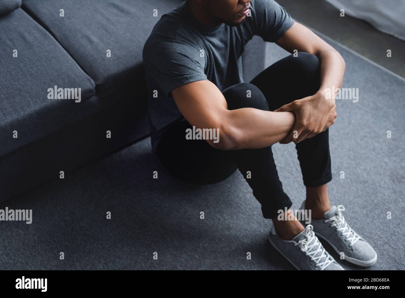 cropped view of sad african american man sitting on floor at home Stock Photo