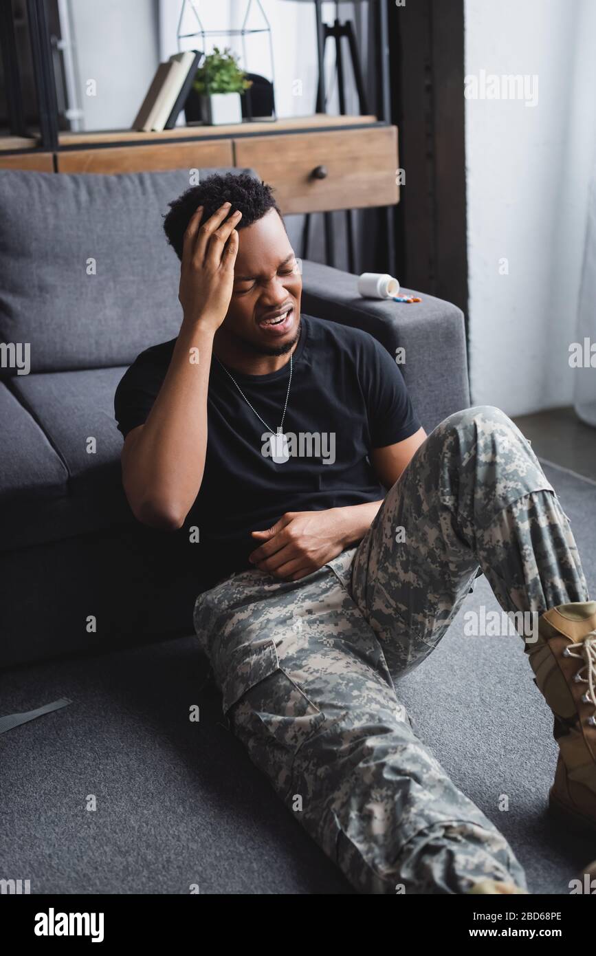 crying african american soldier with army badge suffering from PTSD at home Stock Photo