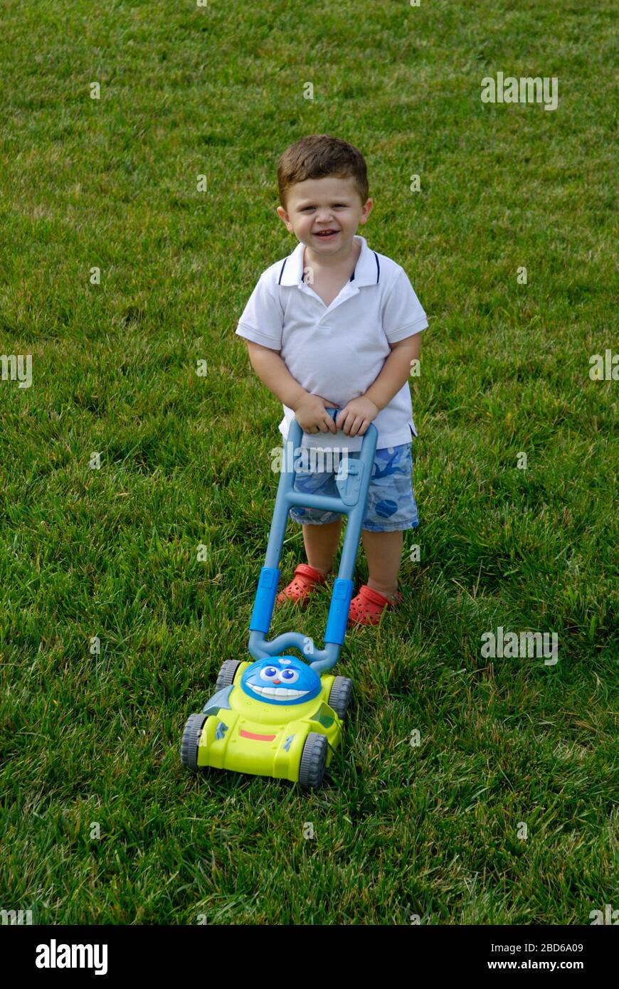 Boy with toy lawn mower Stock Photo