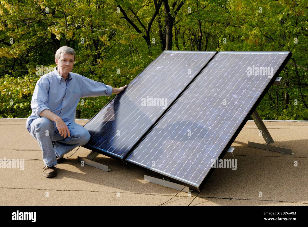 Man with solar panels on roof of house Stock Photo