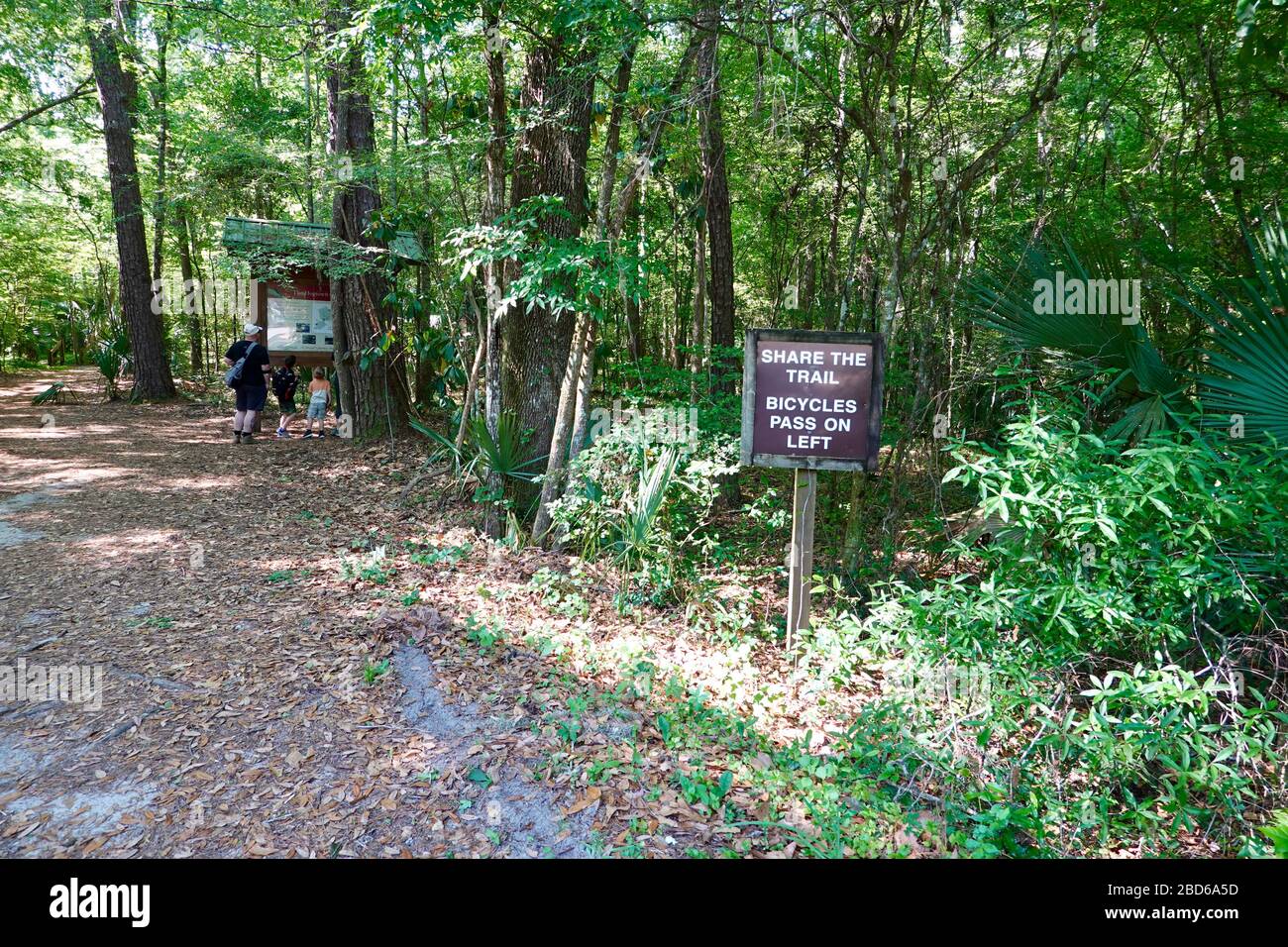 Share the trail, bicycles pass on the left sign, family in background