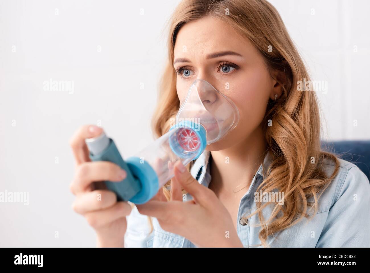 selective focus of asthmatic woman using inhaler with spacer Stock Photo