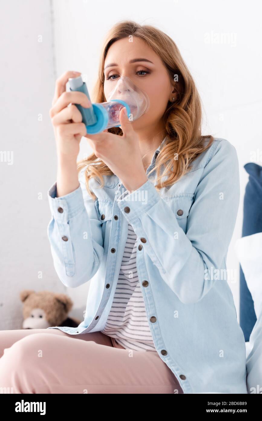 selective focus of sick woman with asthma using inhaler with spacer Stock Photo