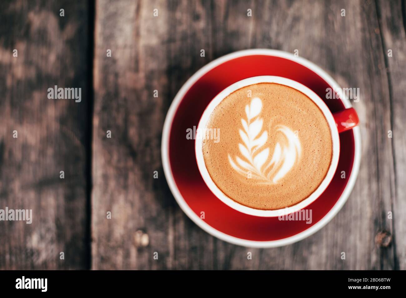 Red cup of cappucino with beautiful latte art on old wooden background. Top  View Stock Photo - Alamy