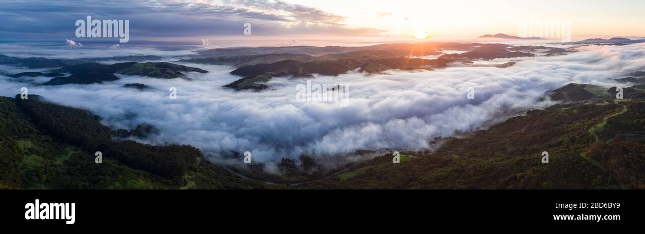 A beautiful sunrise illuminates fog as it rolls through valleys in Northern California. Just west of these hills and valleys is San Francisco Bay. Stock Photo