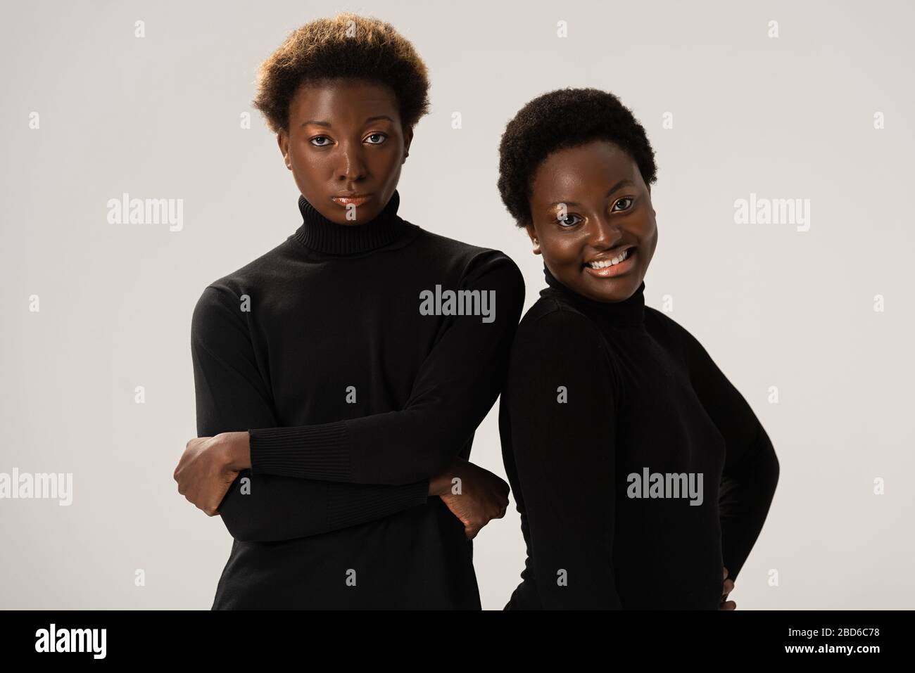 smiling african american girlfriends in black turtlenecks with crossed ...