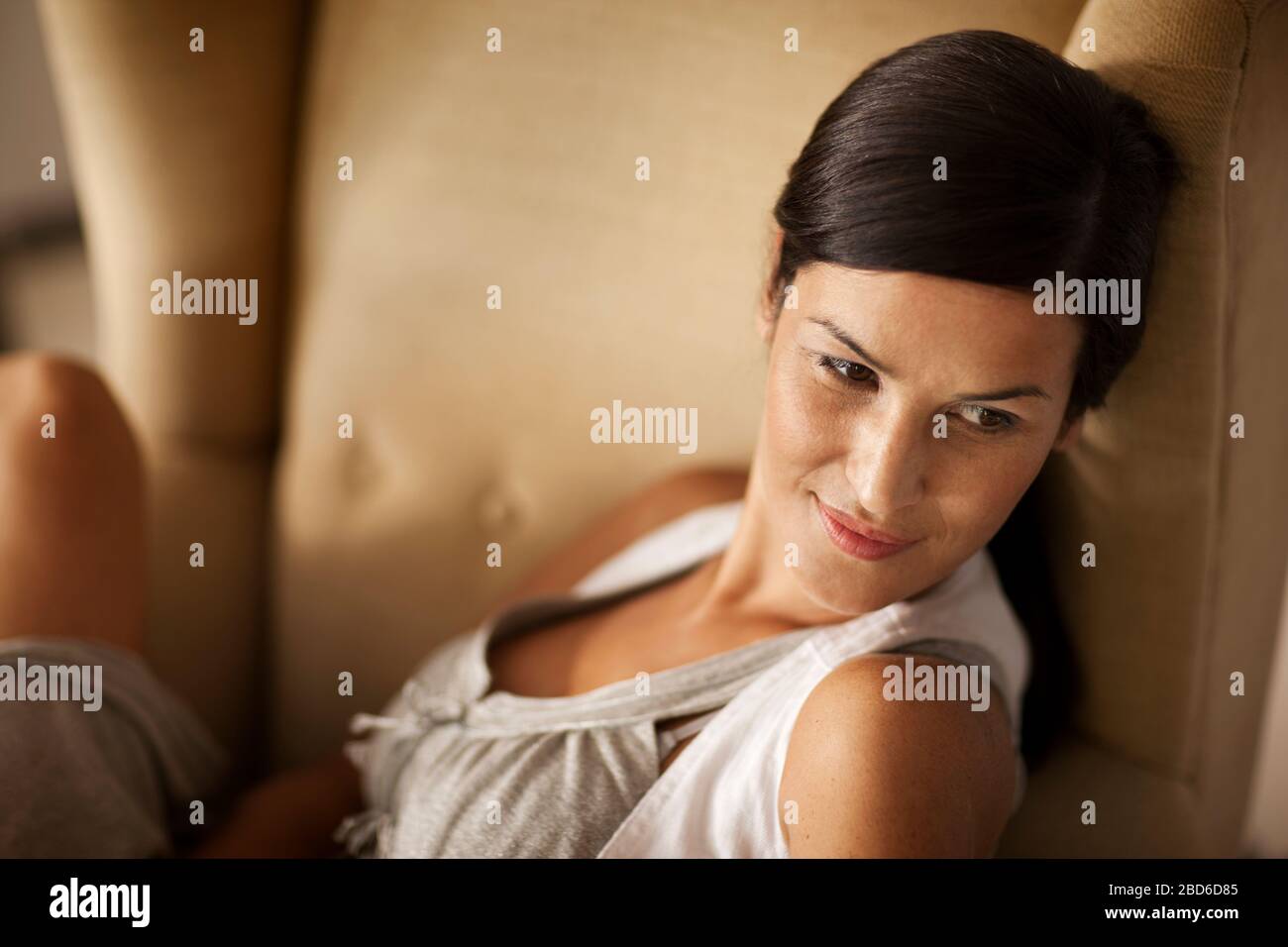 Attractive brunette sits in an arm chair. Stock Photo