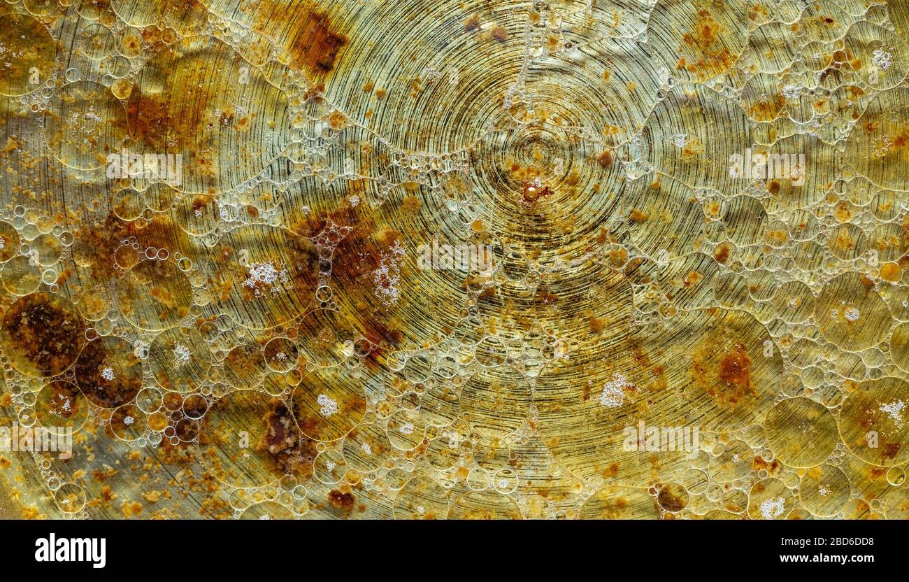 Oil stains on the water. Yellow brown background. Oil in a frying pan. Stock Photo