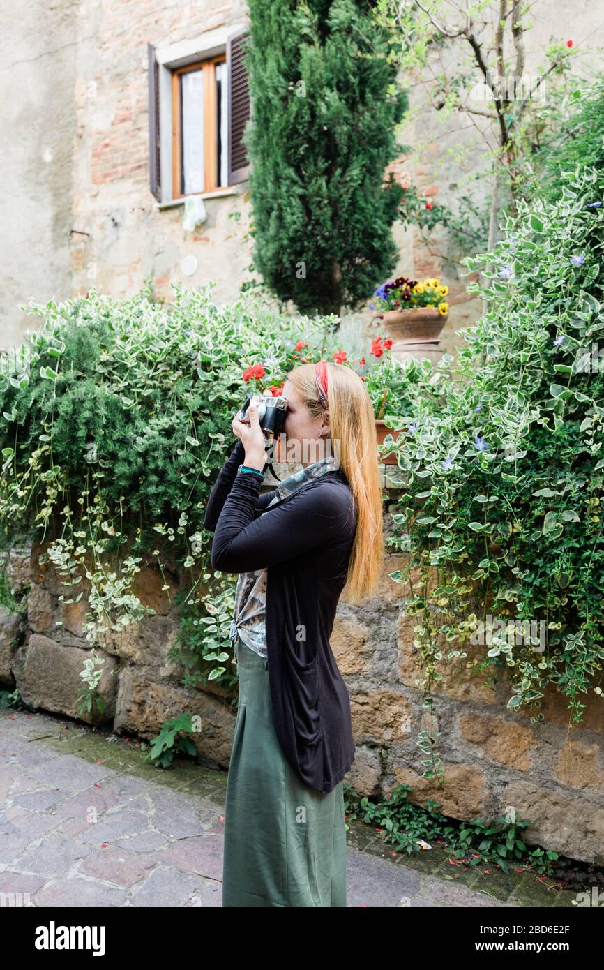 Young female traveler taking a picture in an old town in Tuscany, Italy Stock Photo