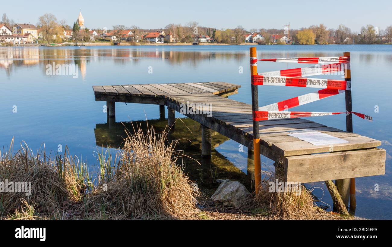 Jetty closed off with barrier tape. Due to the restrictions implemented by the bavarian government to flatten the curve (Covid-19, Coronavirus). Stock Photo