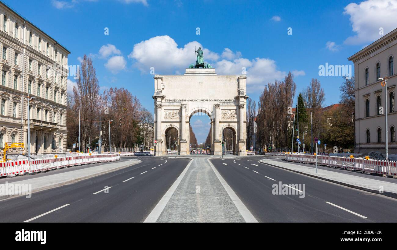 Panorama of Siegestor (victory gate). Rear view with empty Ludwigstraße in the foreground. With blue sky and white clouds. A landmark of Munich. Stock Photo