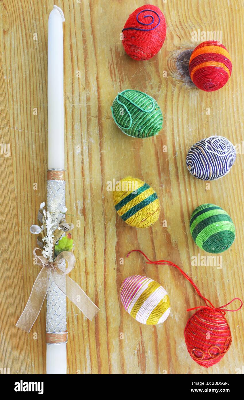 Eggs decorated with threads and an Easter candle on wooden table Stock Photo