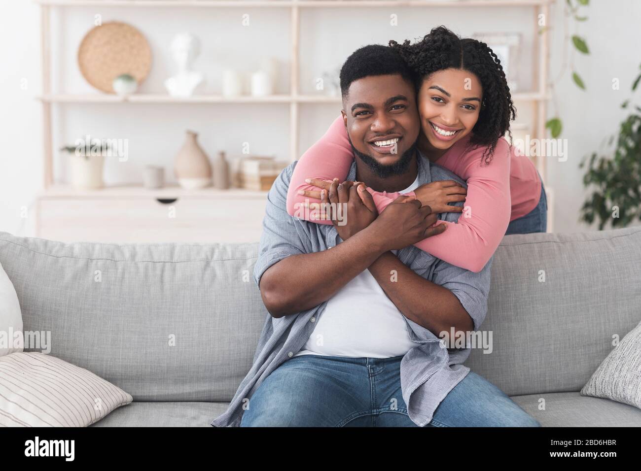 Happy african american couple embracing at home and smiling to camera ...