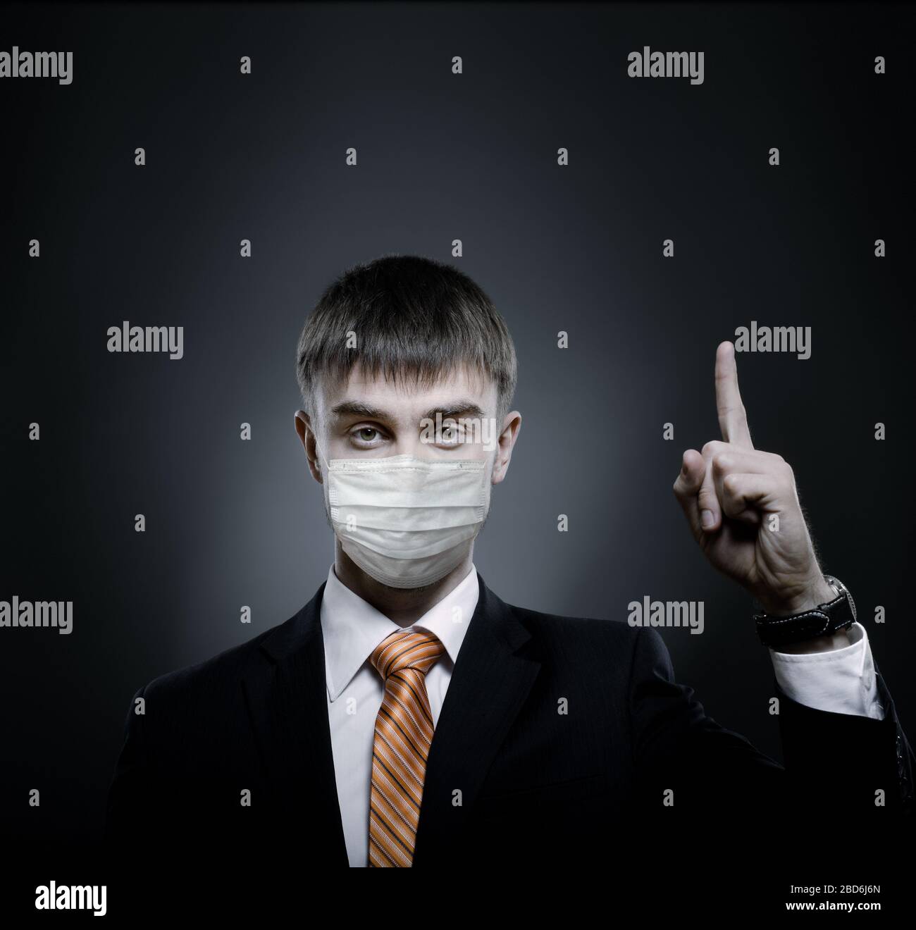 concept coronavirus epidemic, portrait businessman in medical mask, black costume and orange necktie, face closeup Stock Photo