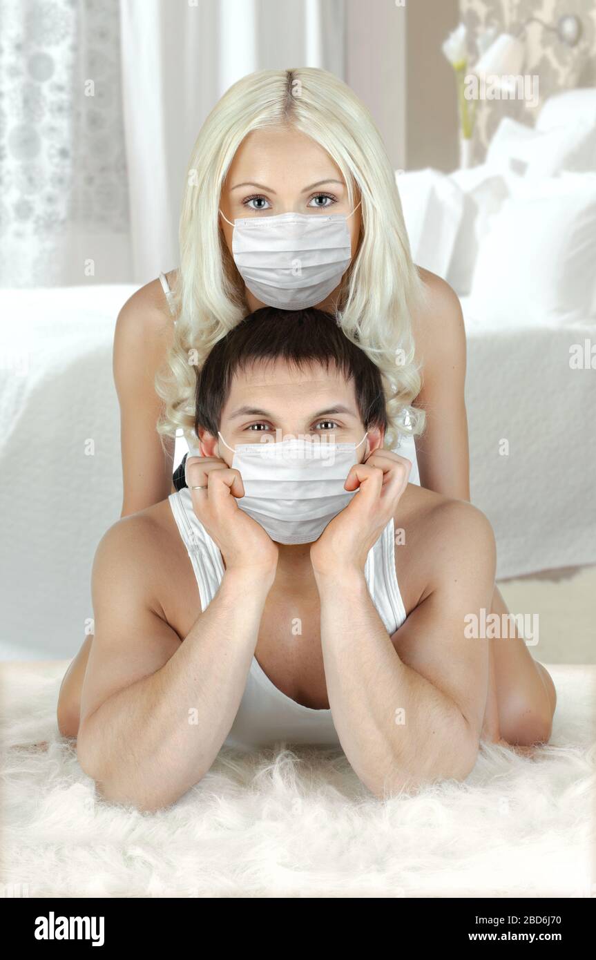 pretty couple in medical mask, lie on floor in home, concept coronavirus covid-19 epidemic Stock Photo