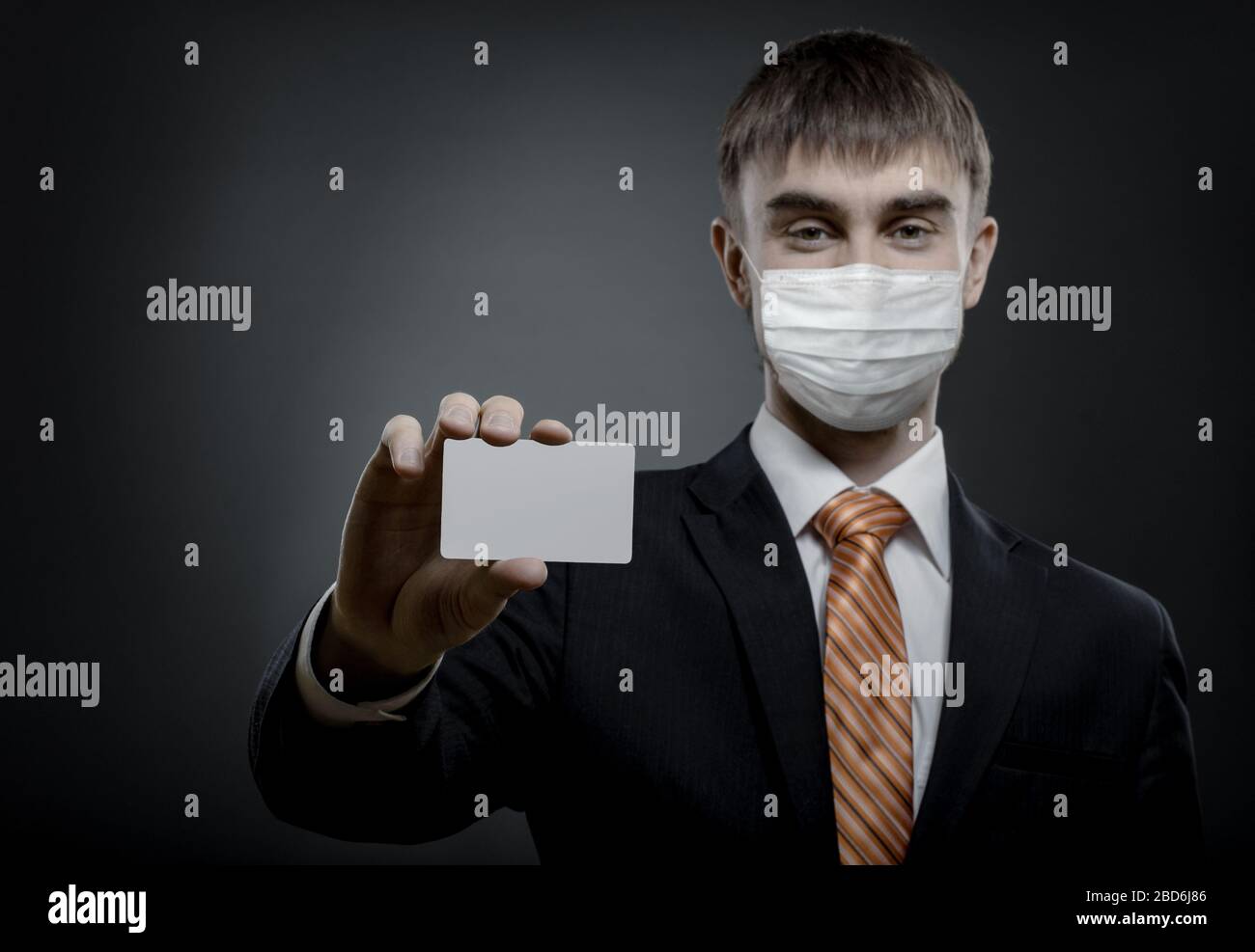 concept coronavirus epidemic, portrait businessman in medical mask show credit card or visiting card Stock Photo