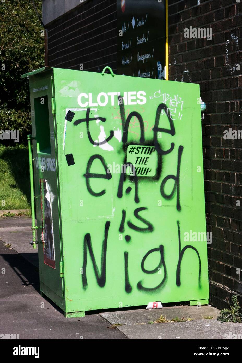 Graffiti, the end is Nigh sprayed on a green clothes recycling bin Stock Photo