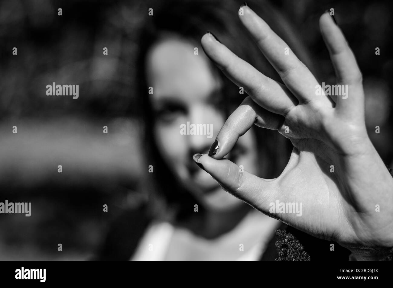 Young woman making ok sign with the hand. Happy girl giving satisfied and supportive hand gesture. Focus on the hand. Stock Photo