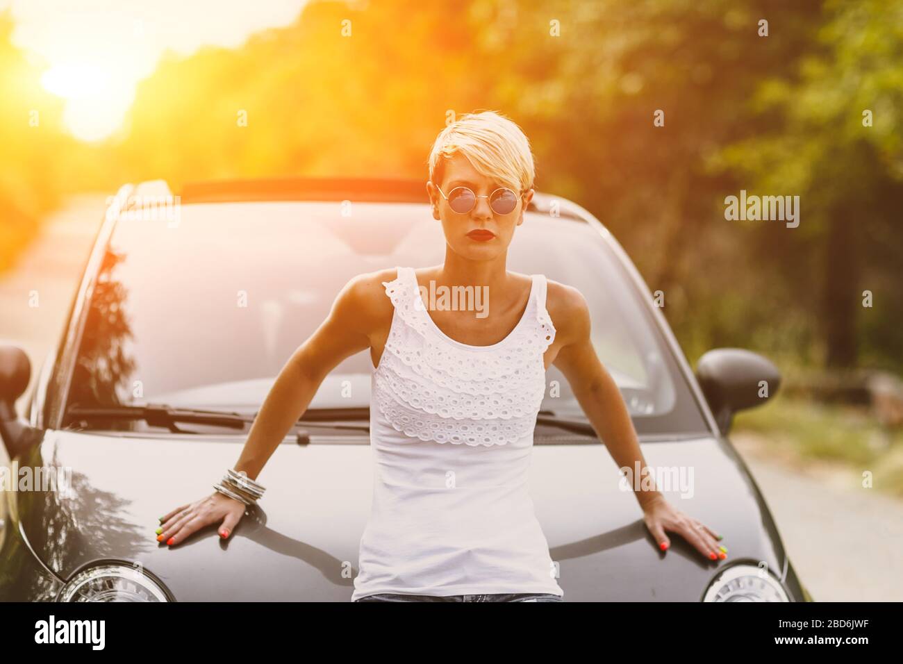 Young pretty fashionable woman posing on a car. Concept young lifestyle. Stock Photo
