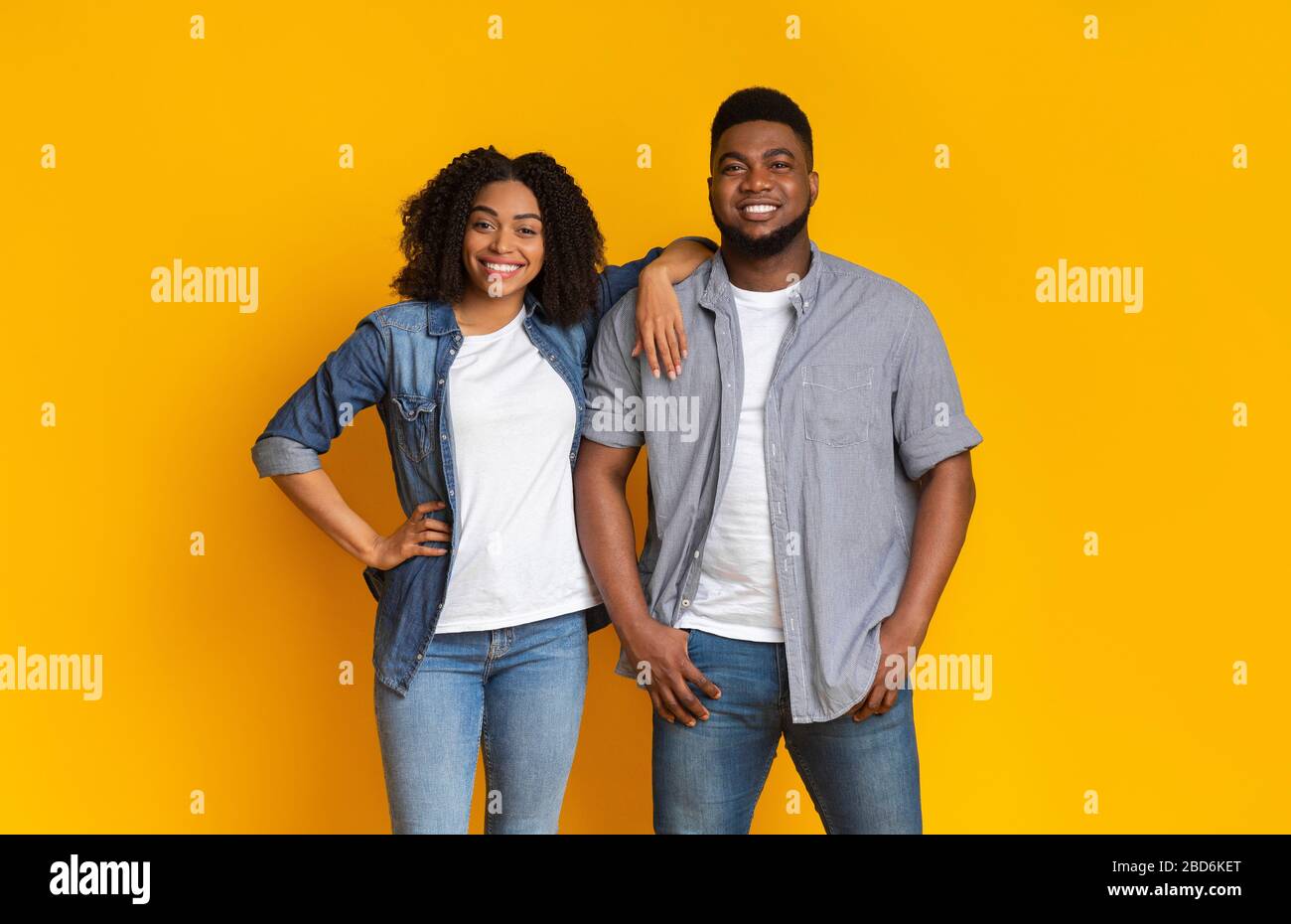 Cool Millennials. Attractive young black couple posing together over yellow background Stock Photo