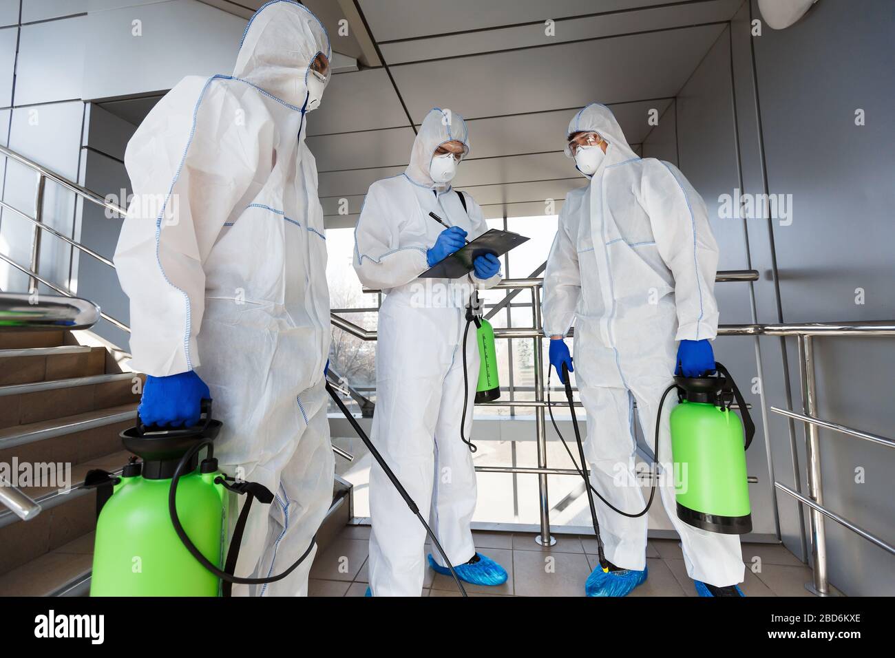 Outdoor disinfection by cleaning workers in hazmat suits Stock Photo