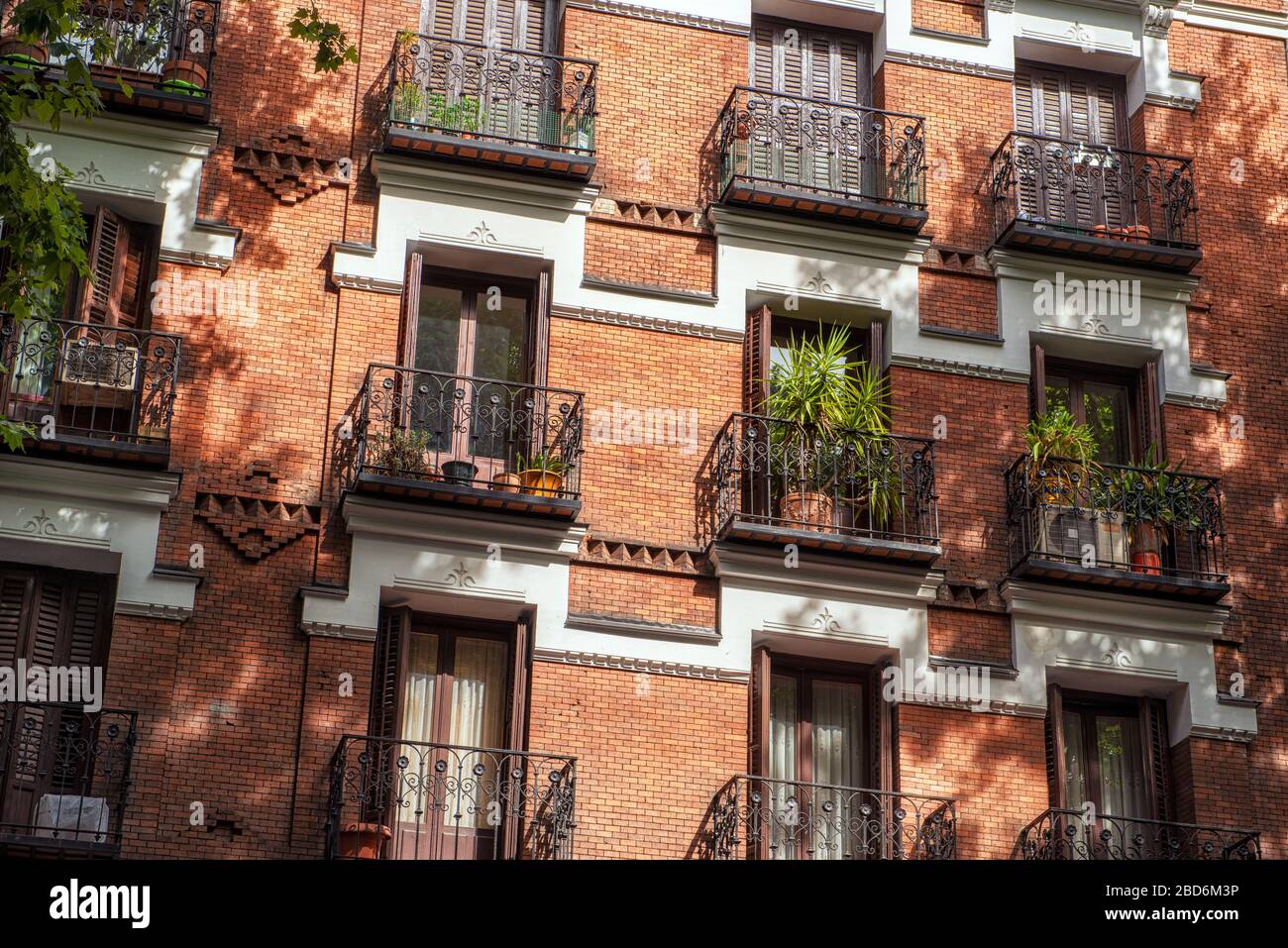 Looking up at elegant shuttered balconies on the side of a red-brick period building Stock Photo