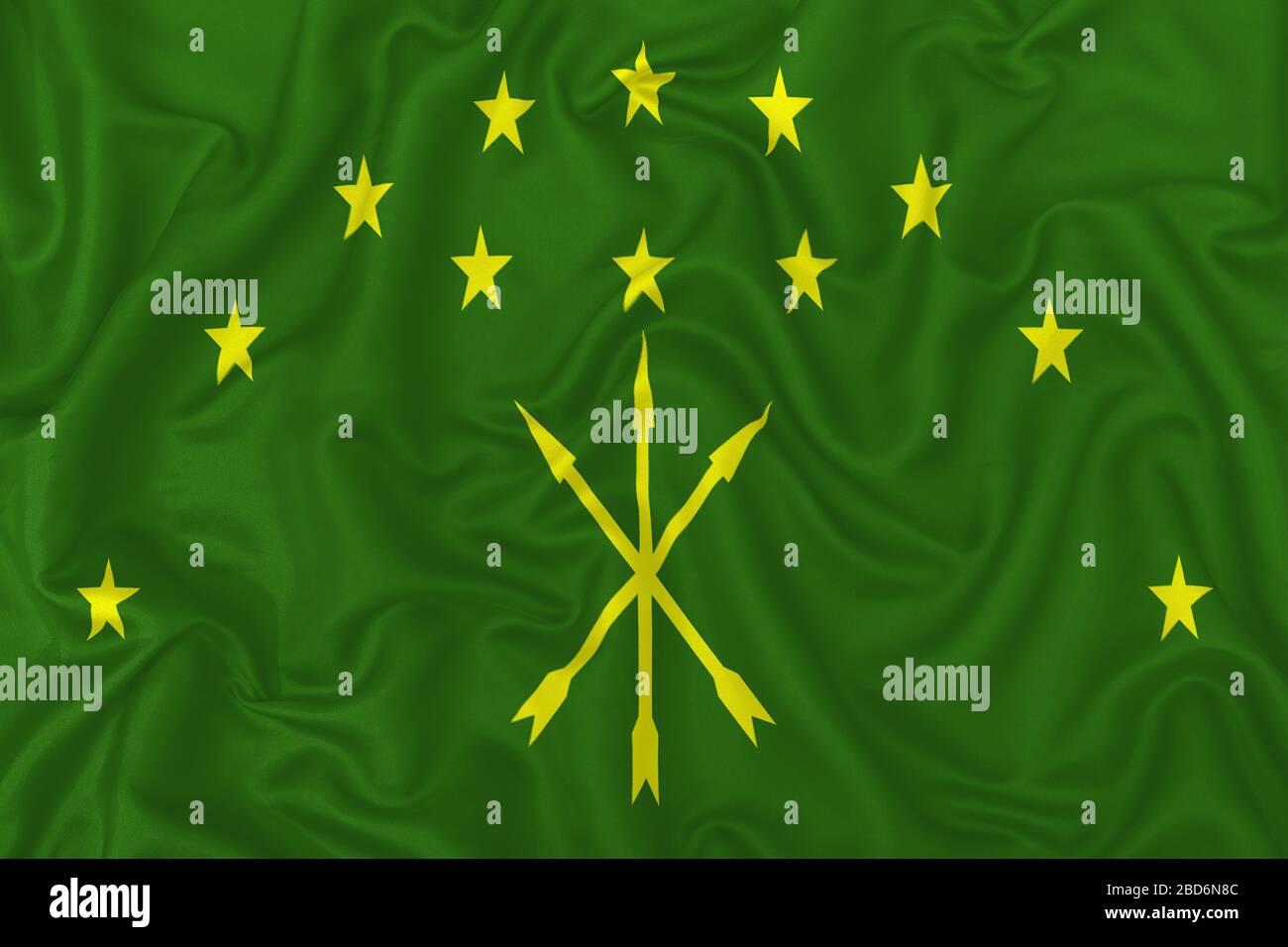 Republic of Adygea flag on wavy silk textile fabric background. Stock Photo