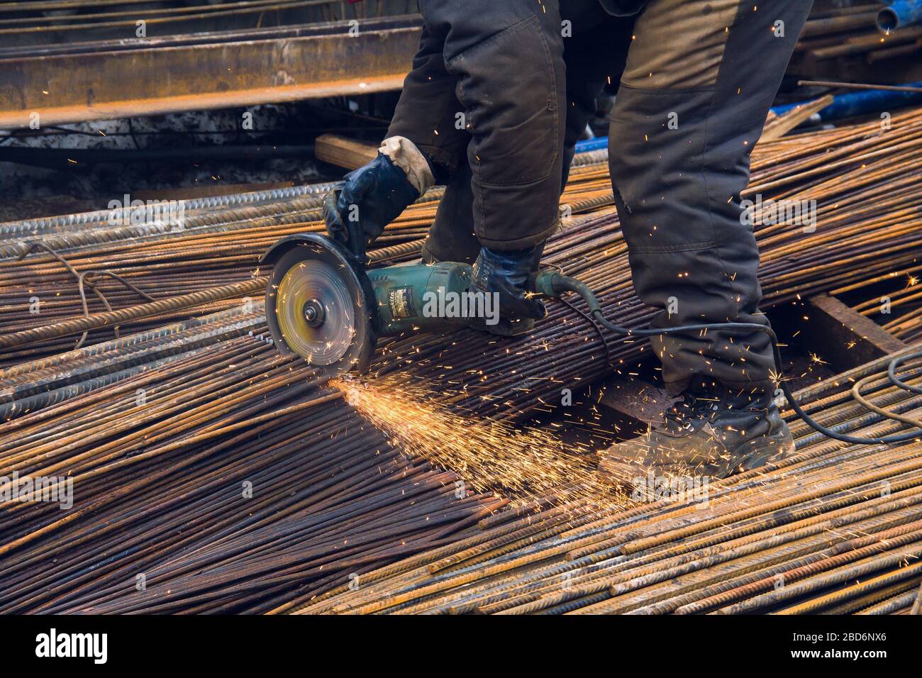 Izhevsk, Russia-April 06.2020: Worker with Angle Grinder Makita cuts steel rods Stock Photo