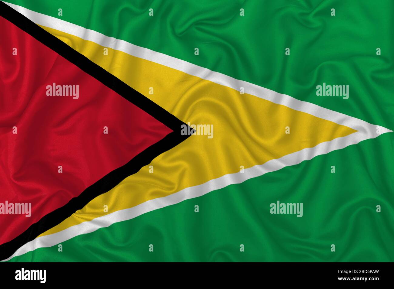 Guyana country flag on wavy silk textile fabric background. Stock Photo