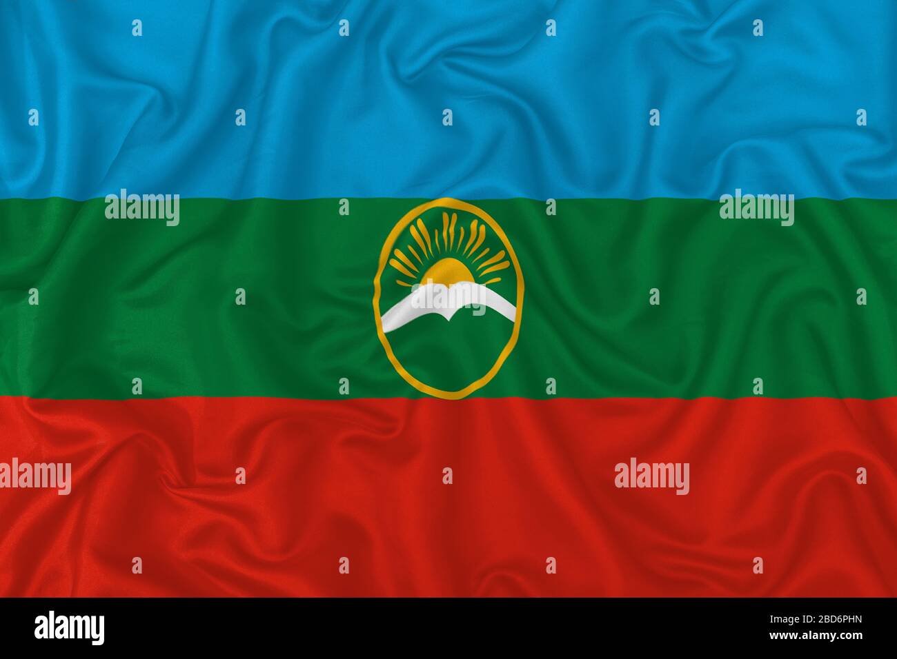 Karachay-Cherkess Republic flag on wavy silk textile fabric background. Stock Photo